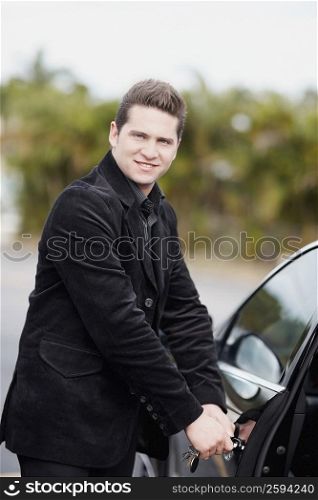 Portrait of a young man opening the door of a car