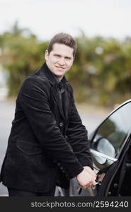 Portrait of a young man opening the door of a car