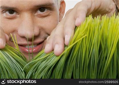Portrait of a young man parting grass saplings with his hands