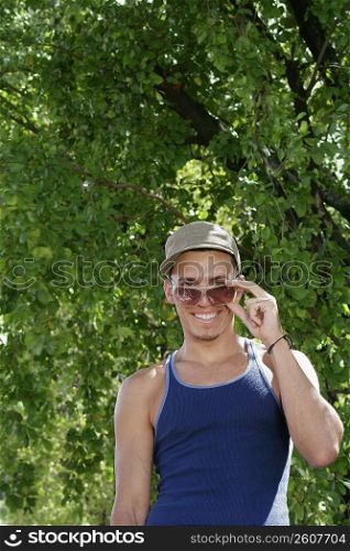 Portrait of a young man peeking over his sunglasses