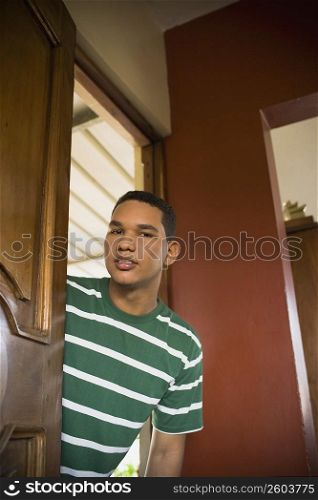 Portrait of a young man peeking through a door