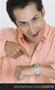 Portrait of a young man pointing at his wristwatch