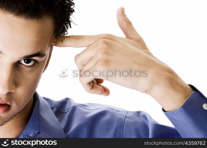 Portrait of a young man pointing to the side of his head