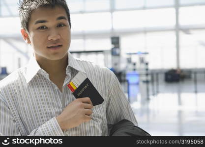 Portrait of a young man putting a passport with an airplane ticket in his shirt&acute;s pocket