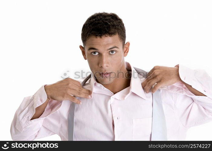 Portrait of a young man putting on a tie