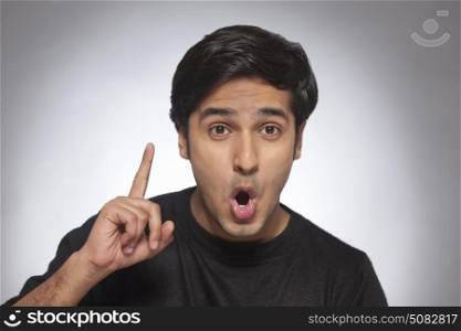 Portrait of a young man raises his finger to make a point