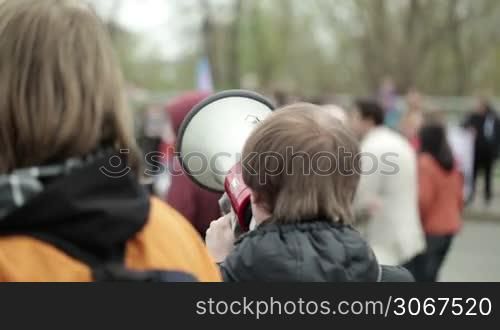 Portrait of a young man shouting with a megaphone at a crowded place