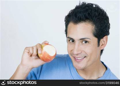 Portrait of a young man showing a missing bite apple and smiling