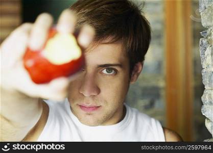 Portrait of a young man showing a partially eaten apple