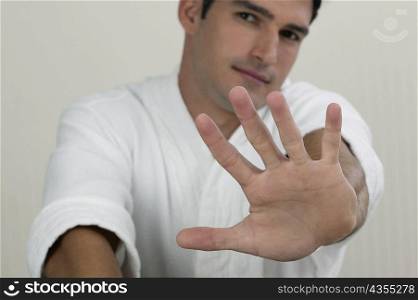 Portrait of a young man showing a stop gesture