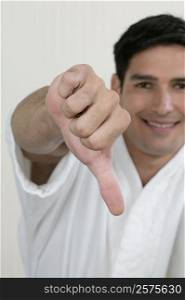 Portrait of a young man showing a thumbs down sign