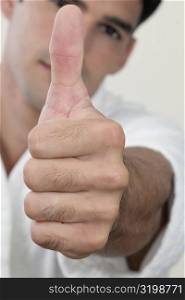 Portrait of a young man showing a thumbs up sign
