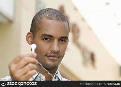 Portrait of a young man showing an ear bud and smiling