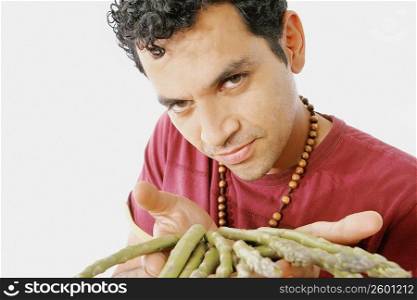 Portrait of a young man showing asparagus