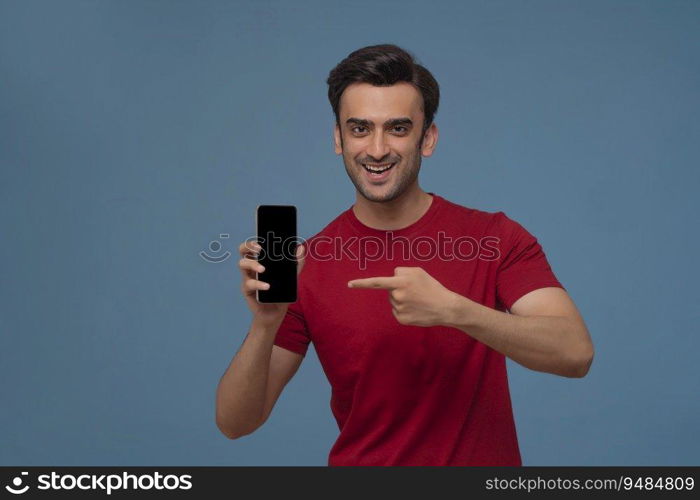 Portrait of a young man showing mobile phone in his hand against plain background.