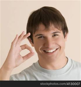 Portrait of a young man showing OK sign and smiling