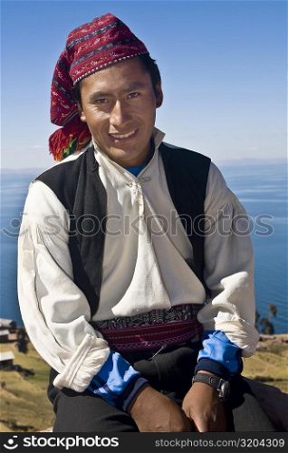Portrait of a young man sitting and smiling, Taquile Island, Lake Titicaca, Puno, Peru