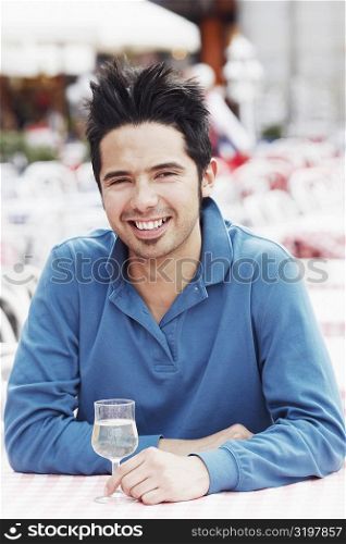 Portrait of a young man sitting at a table in a sidewalk cafe