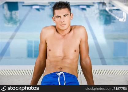 Portrait of a young man sitting at the poolside