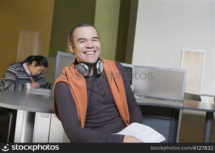Portrait of a young man sitting in a computer lab and laughing