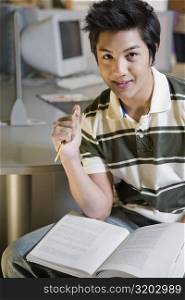 Portrait of a young man sitting in a computer lab and smiling