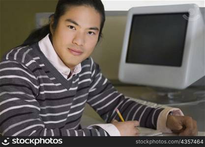 Portrait of a young man sitting in a computer lab and studying