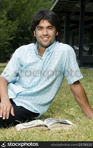 Portrait of a young man sitting in a lawn and smiling
