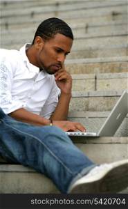 Portrait of a young man sitting in front of a laptop computer