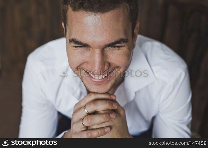 Portrait of a young man sitting on a chair.. Portrait of a man in the background of a wooden wall 6397.