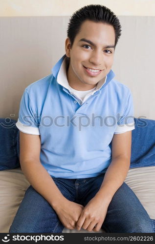 Portrait of a young man sitting on a couch and smiling