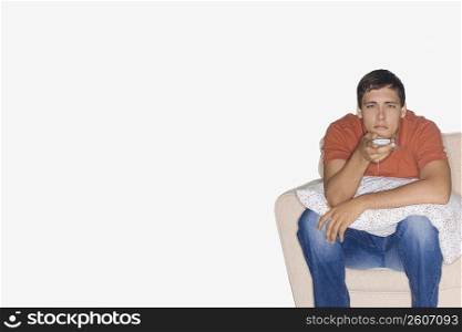 Portrait of a young man sitting on a couch and watching television
