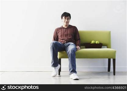 Portrait of a young man sitting on a couch with a fruit bowl beside him