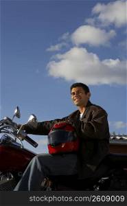 Portrait of a young man sitting on a motorcycle and smiling
