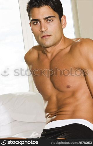Portrait of a young man sitting on the bed thinking