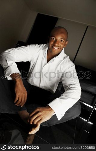 Portrait of a young man sitting on the floor and smiling