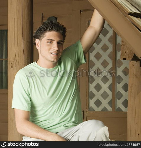 Portrait of a young man sitting on the porch smiling