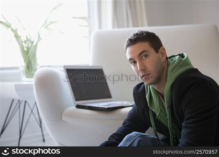 Portrait of a young man sitting with a laptop on a couch