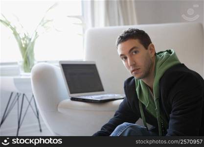 Portrait of a young man sitting with a laptop on a couch