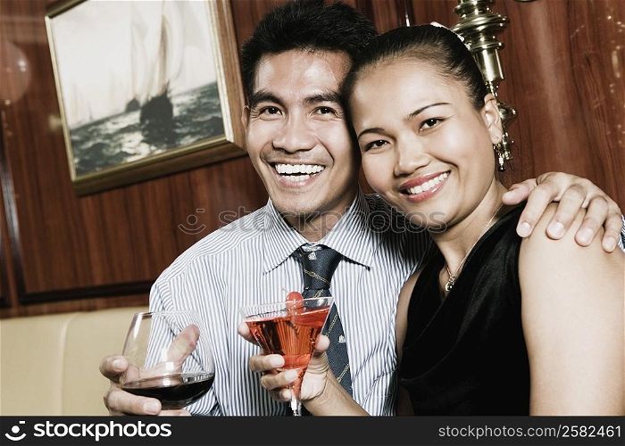 Portrait of a young man sitting with his arm around a young woman and smiling