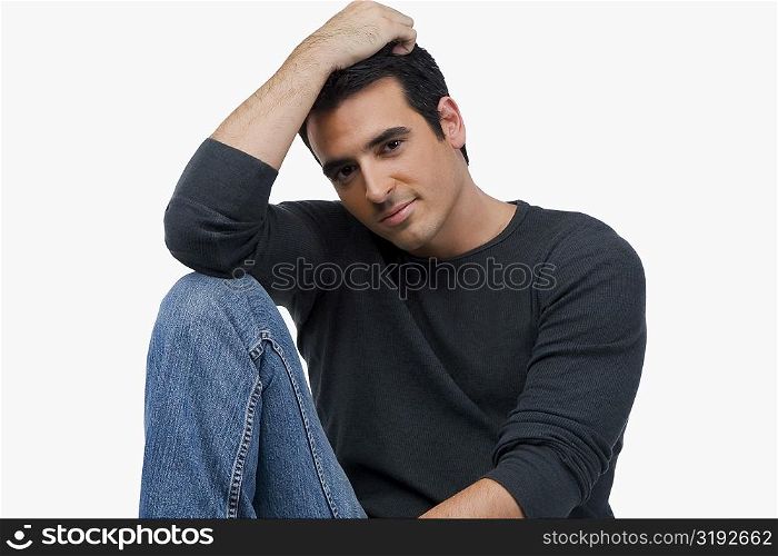 Portrait of a young man sitting with his hand in his hair