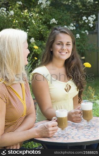 Portrait of a young man sitting with his mother and holding cold coffee cups