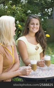 Portrait of a young man sitting with his mother and holding cold coffee cups