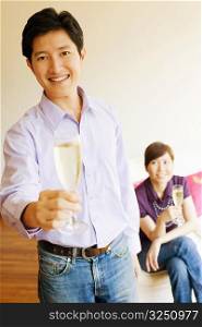 Portrait of a young man smiling and holding a champagne flute