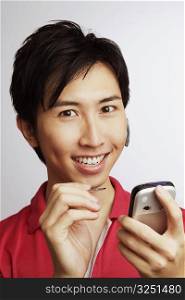 Portrait of a young man smiling and holding a personal data assistant