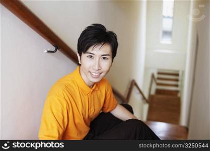 Portrait of a young man smiling and sitting on a staircase