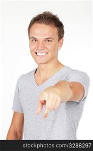 Portrait of a young man smiling, pointing at you. Studio shot. Isolated on white.