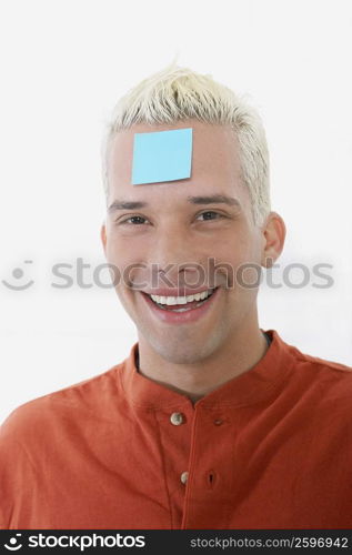 Portrait of a young man smiling with an adhesive note on his forehead