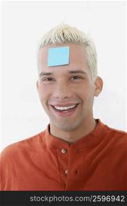 Portrait of a young man smiling with an adhesive note on his forehead