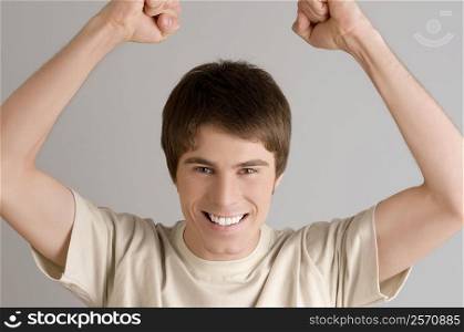 Portrait of a young man smiling with his arms raised