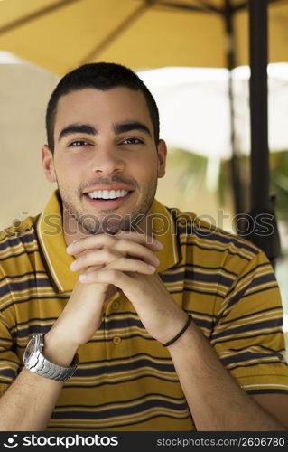 Portrait of a young man smiling with his hands clasped